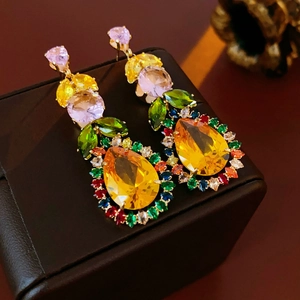 Close-up of leaf-shaped drop earrings with colorful zircon stones in gold setting
