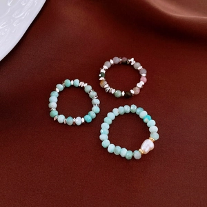 Macro shot of Amazonite and baroque pearl beaded rings on a red velvet texture background