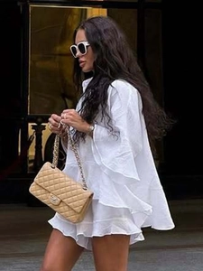 Détails de la robe blanche à manches longues avec volants étagés et texture coton-lin