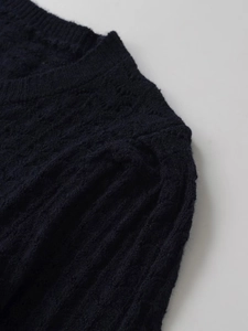 Dettaglio ravvicinato del cardigan blu scuro con maglia a trecce e motivi traforati