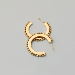 Detail of matte gold C-shape hoop earrings with delicate beaded edge and geometric design