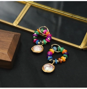 Detailed close-up of bohemian earrings with colored beads and pearl pendant on black cloth
