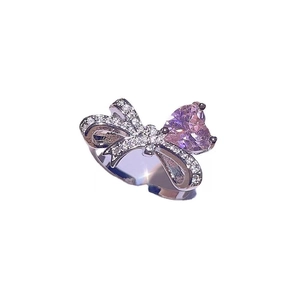 Silver bow ring with sparkling clear stones and a pink heart-shaped crystal center