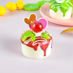 Close-up of artificial fruit cake model with red topping and cherry for home decor