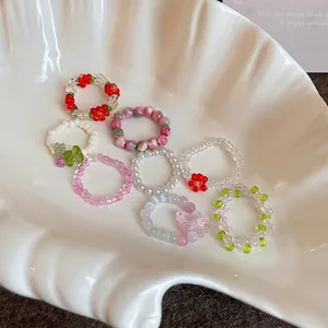 Handmade beaded elastic rings set with floral charms and pearls on a shell tray