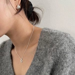 Model wearing minimalist double-layered twisted silver hoop earrings and a matching necklace