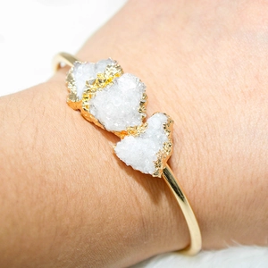 Close-up of gold-plated open bangle featuring three natural raw amethyst crystal clusters