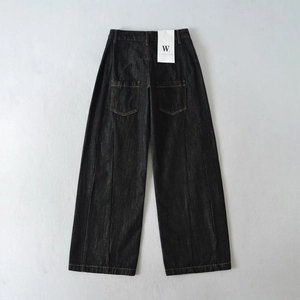 Dettaglio di jeans a gamba larga in denim scuro con cuciture verticali e tasche