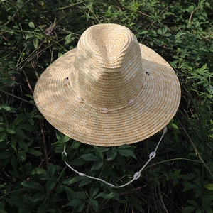 Dettaglio della trama del cappello di paglia con decorazioni di conchiglie bianche