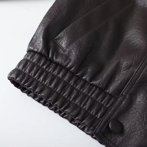 Close-up of faux leather jacket cuff with elastic hem and button detail
