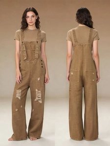 Detail of vintage distressed brown denim overalls featuring ripped finish and wide leg cut