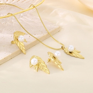 Detail of gold leaf-shaped jewelry set with white pearls on a textured stone surface