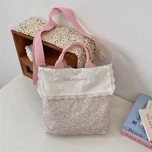 Close-up of floral canvas tote with lace trim and pink embroidery detail on flap