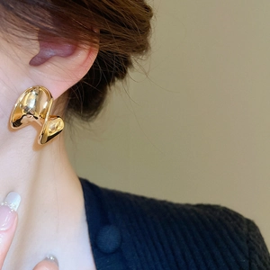 Close-up of elegant gold-plated C-shaped earrings in abstract origami style on model