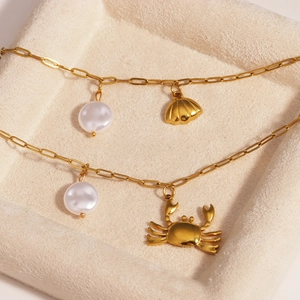 Detail of gold starfish and crab charms with pearls on polished stainless steel chains