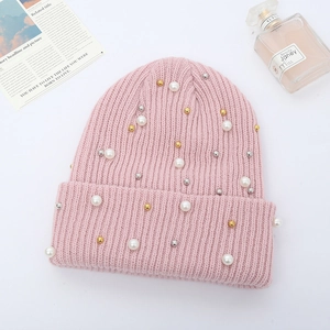 Detail of pink ribbed knit beanie featuring elegant pearl and metallic bead embellishments