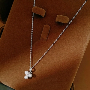 Elegant geometric silver necklace with trio pearl pendant on a velvet jewelry display