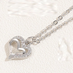 Macro view of silver double heart necklace with sparkling zircon pavé on white paper