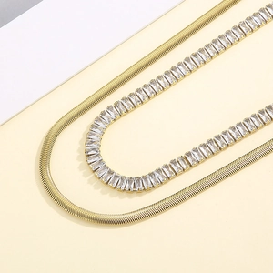 Detail of gold double-layered necklace with flat snake chain and rectangular zircon stone