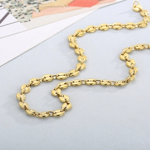 Close-up of golden stainless steel coffee bean link necklace with a polished finish