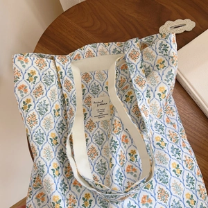 Détail du sac cabas en toile florale avec motif à carreaux bleus et anses en tissu