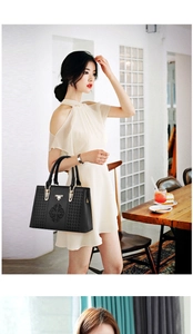 Detail of black tote bag featuring woven texture, gold hardware, and elegant embroidery