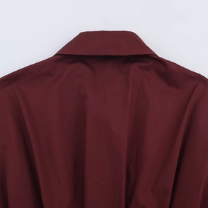 Detailed close-up of the pleated poplin fabric texture and neckline stitching in burgundy