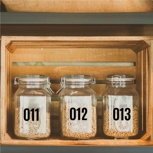 Detail view of numbered waterproof vinyl stickers applied to clear glass storage jars