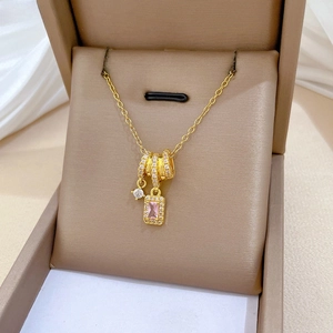 Macro view of gold cylinder pendant with pink rectangular gemstone and pavé diamonds