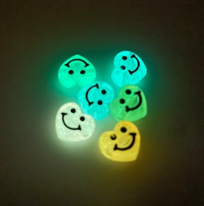 Macro di perline a cuore con faccina sorridente luminose che brillano al buio
