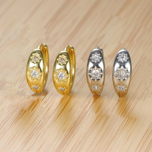 Detailed macro view of gold and silver sunburst hoop earrings with sparkling zircon