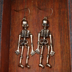 Close-up of vintage bronze skeleton earrings on a dark wood texture background