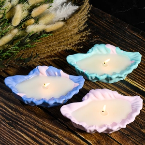 Drie schelpvormige aromatherapiekaarsen met gekleurde marmerpatronen op een houten tafel