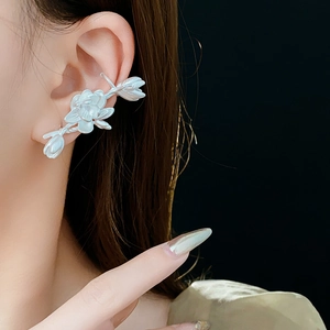 Close-up of a silver lotus ear cuff on a model ear against a black background