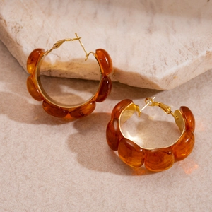 Retro amber resin hoop earrings with gold metal base on natural stone background