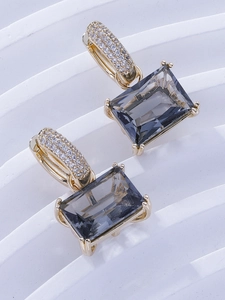 Detail of luxury gold earrings with micro-set zircons and emerald-cut smoke grey stones