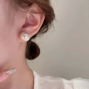 Close-up of a large white pearl earring with a high-luster finish on a model