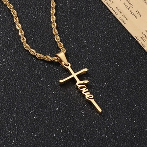Detailansicht goldener Kreuzanhänger mit Love-Schriftzug auf schwarzem Hintergrund