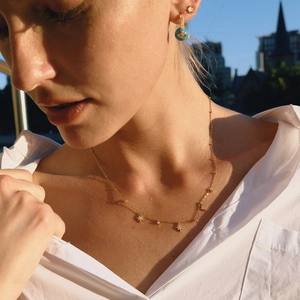 Détail de pendentifs étoile sur collier doré et boucles d'oreilles turquoise sur modèle