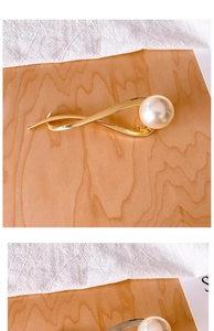 Close-up of elegant gold alloy hair clip featuring a large pearl and streamlined design