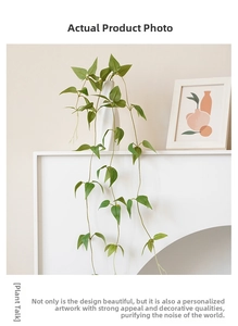 Artificial clematis vine in a white ceramic vase with natural green leaf textures