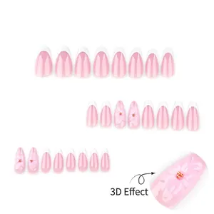 Faux ongles French roses avec fleurs 3D et billes dorées sur un fond blanc propre