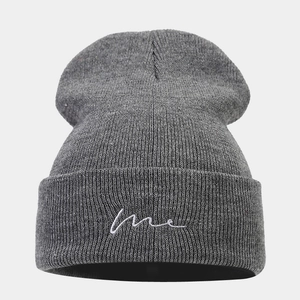 Close-up of ribbed texture and white 'me' embroidery on the dark grey knit beanie
