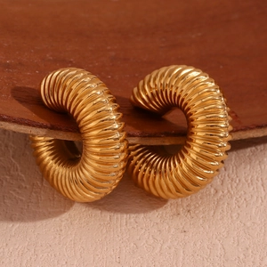 Macro detail of 18K gold plated thick C-shaped hoop earrings with spiral thread texture