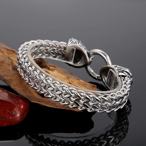 Detailed view of silver stainless steel braided bracelet with lion head clasp on stone