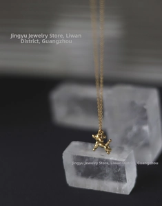 Macro detail of high-polish balloon dog pendant on delicate 18K gold-plated chain