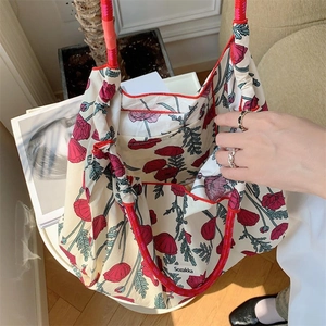 Top view of beige floral tote bag with red rope handles and interior brand label details