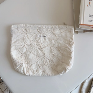 Close-up of minimalist leaf embroidery on cream canvas bag with simple wish label