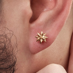 Men's gold stainless steel spiked piercing stud earring shown on a model's ear