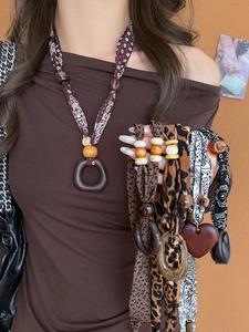 Detail of ethnic fabric scarf necklace with leopard print beads and heart pendant